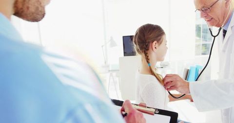 Senior doctor conducting health checkup on young girl