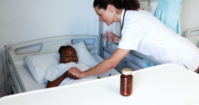 Nurse holding patient's hand while young child lies in hospital bed, ensuring patient comfort and care. Nurse offers medicine and water. Ideal for use in healthcare, medical care, and hospital-related promotions.