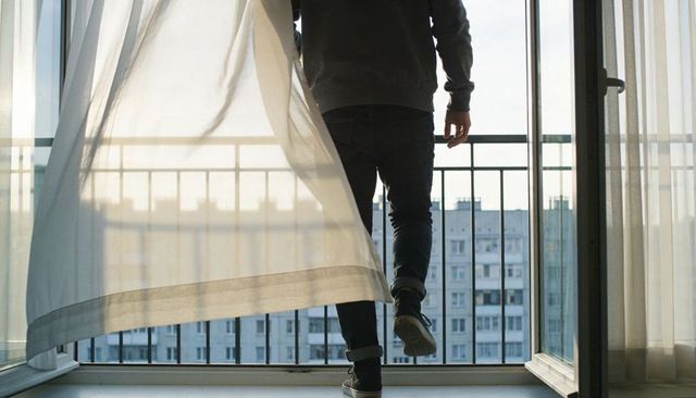 Stepping onto balcony at sunrise, urban high-rise silhouette with curtain breeze