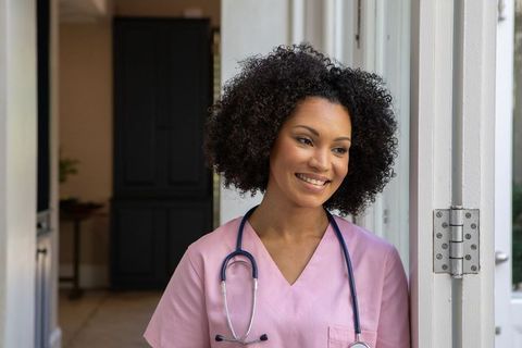 Confident Nurse Smiling in Clinic Doorway with Stethoscope Around Neck