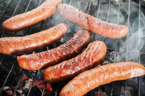 Smoky charcoal-grilling sausages sizzling and charring on hot grill for summer barbecue