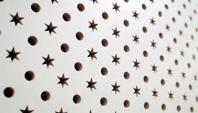 White perforated panel revealing brown wood core through star and round cutouts