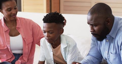 African American Parents Bonding With Son on Sofa During Quiet Family Moment