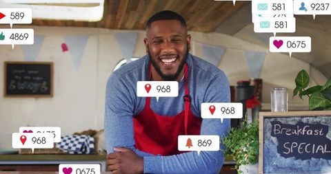Smiling barista leaning on rustic counter showing social media engagement at cozy cafe