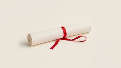 Parchment scroll with red ribbon on cream surface