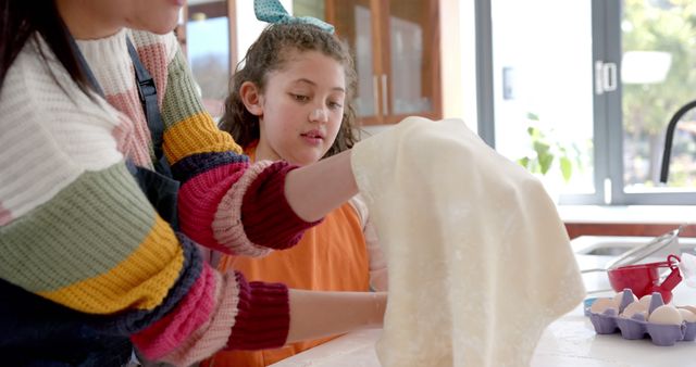 Mother assisting daughter in kitchen while preparing dough, ideal for lifestyle and parenting articles, baking blogs, family-oriented advertisements, and recipe websites. Emphasizes home baking, family bonding, and spending quality time together.