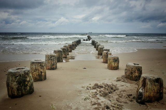 Weathered Wooden Posts Leading into Ocean on Overcast Day - Download Free Stock Photos Pikwizard.com