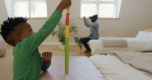 Young Boy Playing with Rainbow Stacking Toy in Bright Room - Download Free Stock Images Pikwizard.com