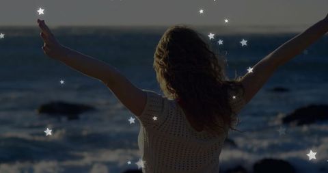 Woman embracing ocean bliss at rocky shore with stars