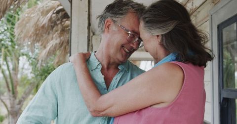 Happy Senior Couple Embracing on Beachfront Porch