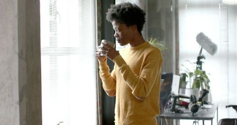 African American Man in Yellow Sweater Drinks Coffee by Window - Download Free Stock Images Pikwizard.com