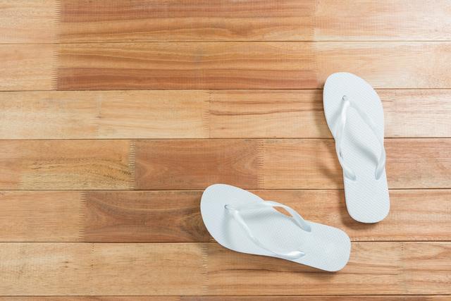 Pair of white beach flip flop slipper on wooden board