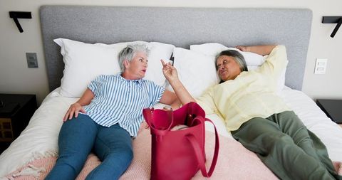 Senior Lesbian Couple Relaxing on Bed Discussing Vacation Plans