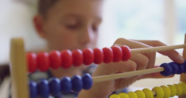 Child using a traditional abacus for learning mathematics. Perfect for educational content, teaching materials, online courses, school-related articles, and promotional materials focusing on early childhood education. Emphasizes educational tools and hands-on learning approaches.