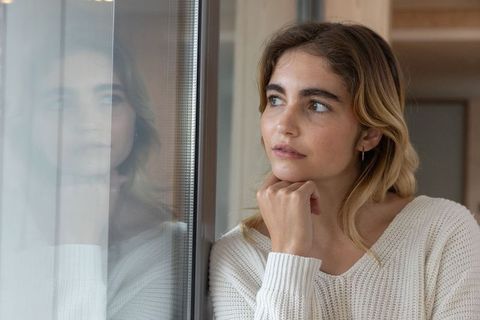 Young Woman in Cozy Sweater Gazing Through Window at Home