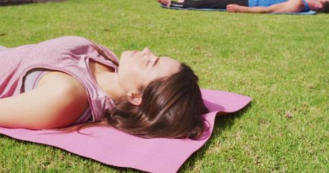 Two People Lying on Pink Yoga Mats Enjoying the Sun in a Garden