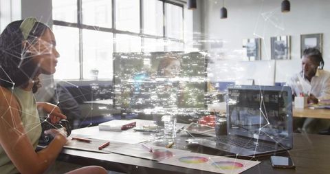 Collaborating woman holding pen at coworking desk with laptop and color wheel charts