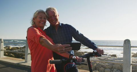 Senior couple enjoying leisurely seaside promenade scooter ride