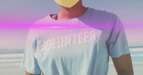 Masked volunteer stands on bright sunny beach for eco conservation