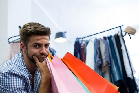 Bored Male Shopper Leaning on Bags in Clothing Store