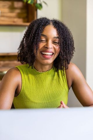 Smiling african american woman using laptop, working remotely at minimalist home desk