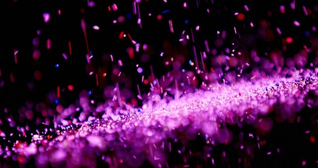 Image showcasing vibrant pink and purple glitter falling against a dark background. Suitable for use in festive and celebration-themed designs, party invitations, and abstract art projects. Excellent for adding a sparkling and dynamic visual effect.