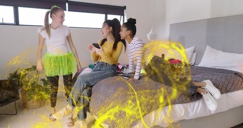 Teen friends chatting in modern bedroom with neon tutu and phone, playful daylight scene
