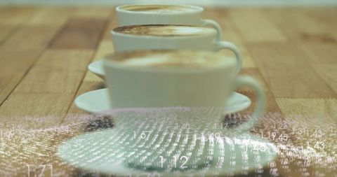 Three white cappuccino cups on wood table with frothy crema and numeric overlay