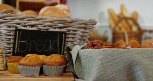 Assorted fresh bread and muffins displayed in a bakery. Wicker baskets hold a variety of baked goods, creating a homely and inviting atmosphere. Perfect for use in scenes depicting morning routines, artisanal food, or showcasing the appeal of local bakeries.