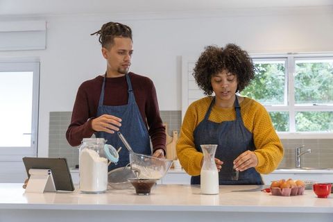 African american couple baking together at bright modern kitchen island using tablet