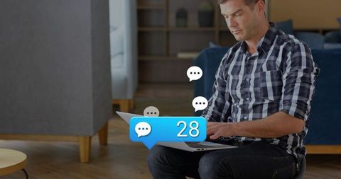Remote worker typing on laptop receiving 28 chat notifications in home lounge