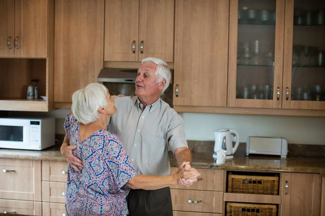 Senior couple dancing together in kitchen at home