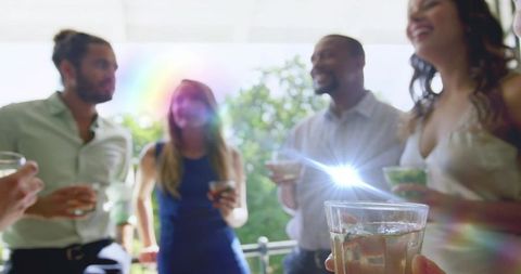 Friends Toasting on Sunny Balcony, Enjoying Drinks and Laughter at Casual Summer Gathering