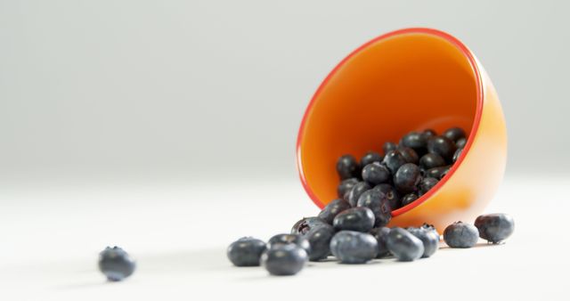 Fresh Blueberries Spilling from Orange Bowl on White Surface - Download Free Stock Images Pikwizard.com