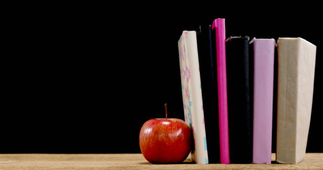 Stack of Books with Red Apple on Wooden Table Against Black Background - Download Free Stock Images Pikwizard.com