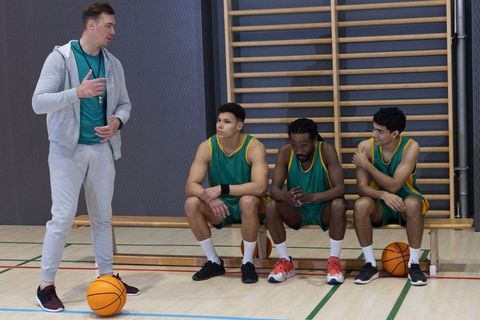 Diverse basketball team receiving coaching guidance on indoor court