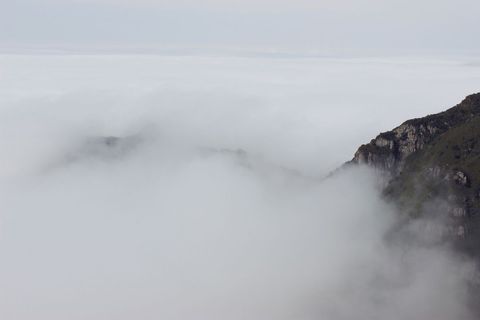 Misty mountain peak emerging above clouds