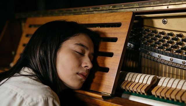 Resting pianist leaning on upright piano with exposed strings, warm woodgrain closeup