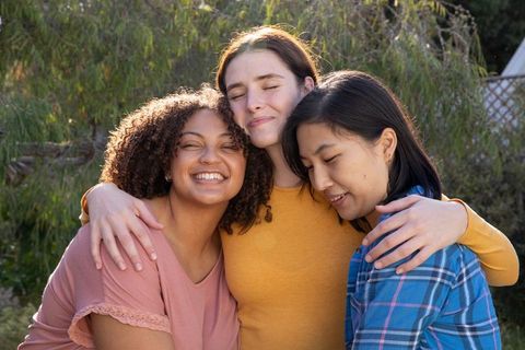 Diverse friends hugging in sunny garden showing friendship and joy
