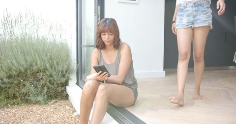 Young Woman Looking Concerned While Friends Connect at Home