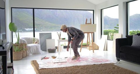 Indian artist working in bright coastal living room studio with easel and mountain view