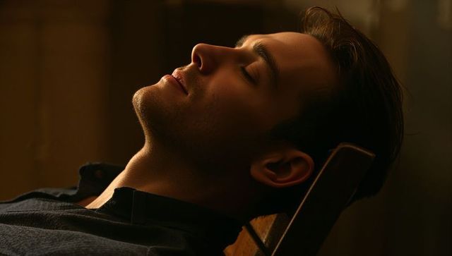 Moody low-key portrait of reclining young man in warm chiaroscuro studio light