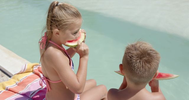Children are sitting by a swimming pool, enjoying watermelon slices on a sunny summer day. They appear to be siblings, with the girl in a pink swimsuit and the boy wearing swim trunks. This refreshing moment captures the essence of carefree summer days and can be used for promoting family vacations, healthy eating habits, swimwear, or summer activities.