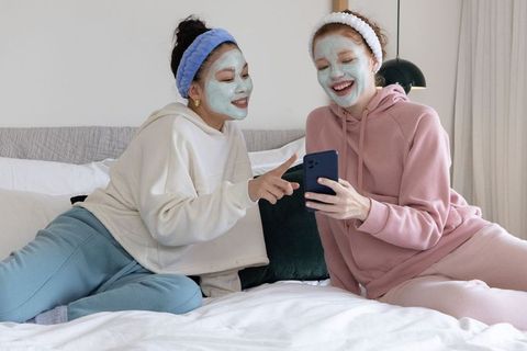 Female friends enjoying at-home spa night, face masks and cozy loungewear