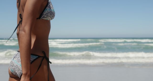 Side view of young African american woman in bikini on beach in the sunshine. She is walking towards the sea 4k