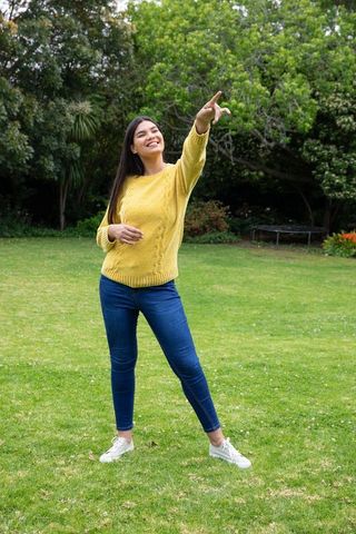 Woman in Mustard Sweater Enjoying Outdoor Leisure in Lush Garden