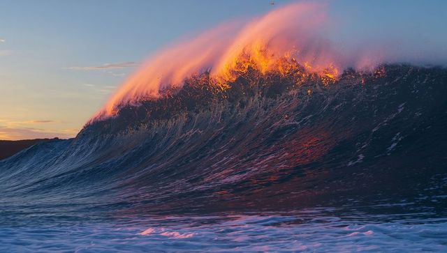 Vibrant ocean wave at sunset with radiant spray