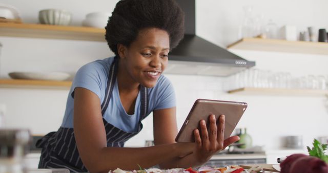 Happy african american woman preparing dinner using tablet in kitchen. domestic lifestyle, spending free time at home.