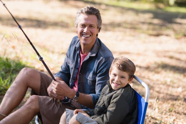 Portrait of cheerful father and son fishing on sunny day