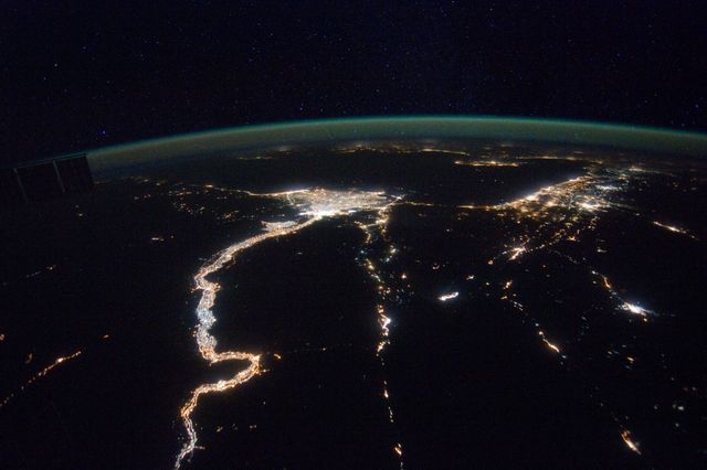 Impressive night capture showing Earth from space, highlighting the illuminated Nile River, Alexandria, and surrounding regions. River lights and city lights create a striking contrast against the dark landscape. Useful for educational materials about geography or astronomy, presentations on space exploration, and promoting travel to these regions.